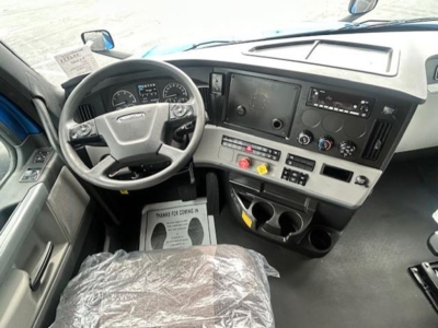 Truck cab interior showing steering wheel, dashboard with gauges, center console, and radio/display panel.