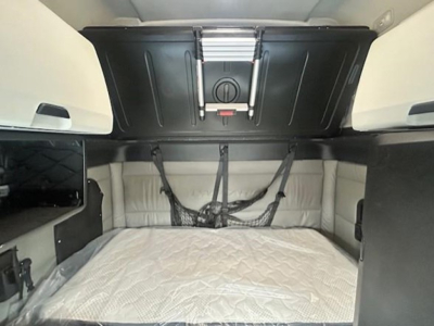 Freightliner Cascadia sleeper cab interior showing bunk area with mattress and overhead storage hatch.