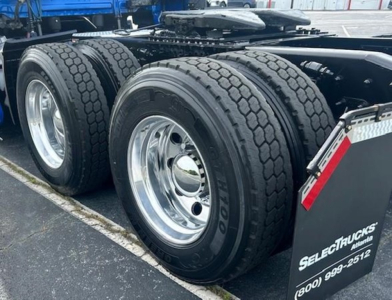 Rear triple-axle truck wheels with Goodyear tires, chrome rims, and a black mudguard showing Select Trucks Enterprises branding.