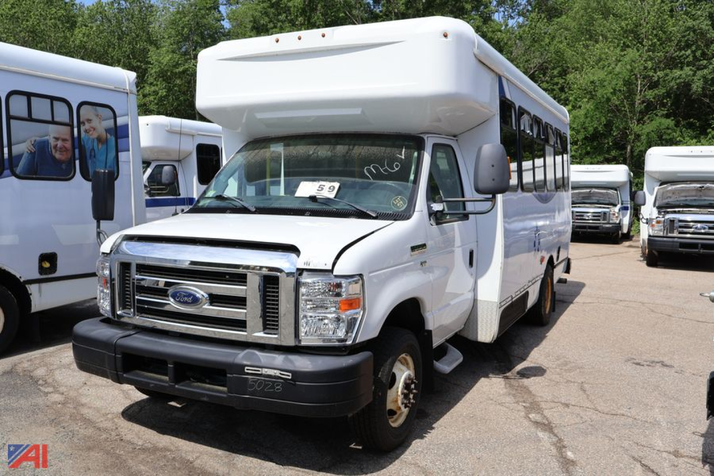 Ford E350 wheelchair bus, white, front view with raised roof and wheelchair access, parked among other buses.