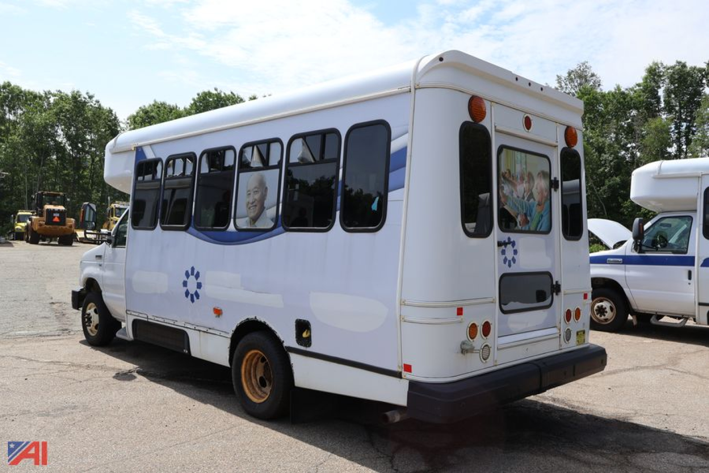 Ford E-350 wheelchair bus rear three-quarter view with white body and blue stripe accents.