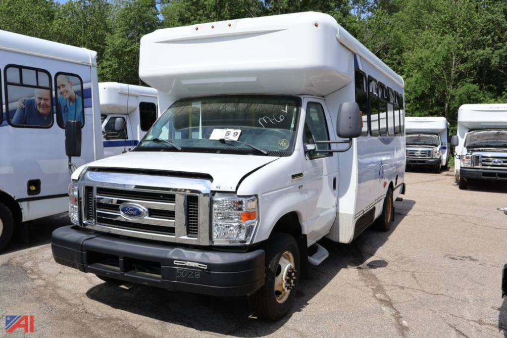 Ford E350 wheelchair bus, white, front view with raised roof and wheelchair access, parked among other buses.