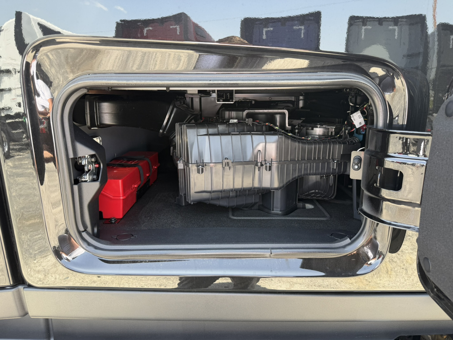 Truck sleeper cab storage compartment with visible fuel system and battery in a Mack PR64T76H engine bay/side locker.