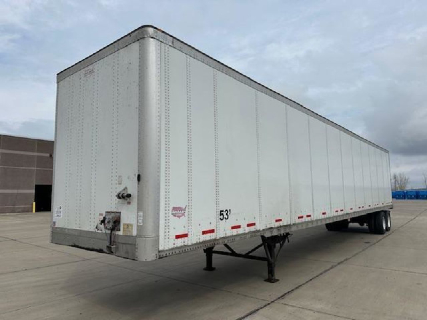 Trailer: 2014 Wabash box trailer in-service showing front hitch and landing gear, side panels with riveted aluminum exterior, 53' length, white color.