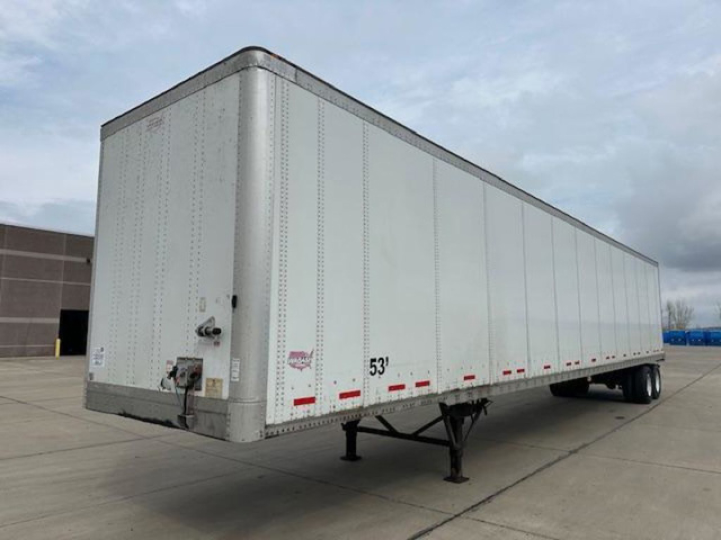 Trailer side view showing 53' Wabash van trailer with landing gear, front toe hitch, and riveted aluminum exterior.