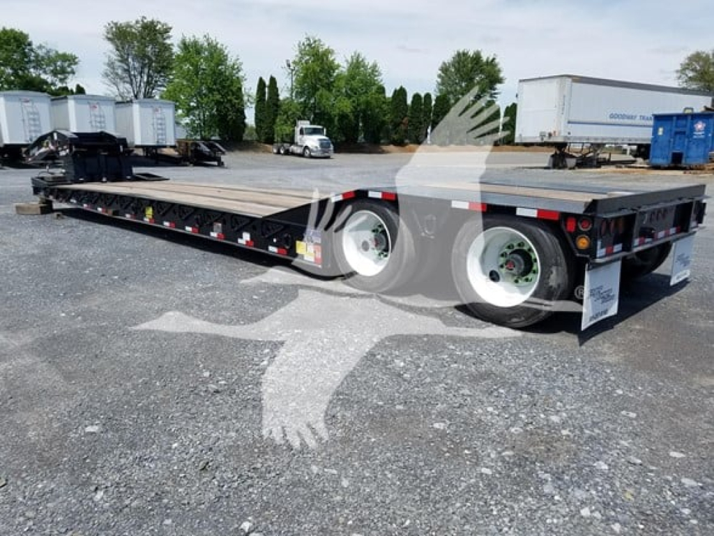 Flatbed trailer with dual rear axles and metal deck, black frame, white wheels, and reflective tape.