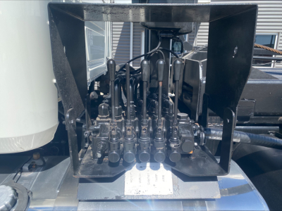 Mack GU533 control valve levers and hydraulic manifold block visible in a truck bed, with multiple black levers and cables inside a metal frame.