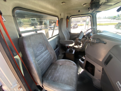 Cab interior of a Mack GU533 truck showing driver's seat and steering wheel; visible text on window reveals nothing legible.