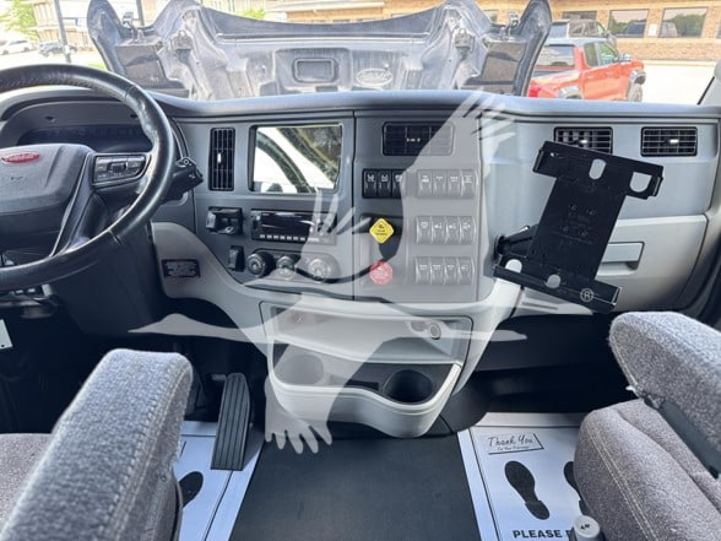Cab interior of 2023 Peterbilt 579 conventional sleeper truck showing steering wheel, dashboard controls, and driver seat.