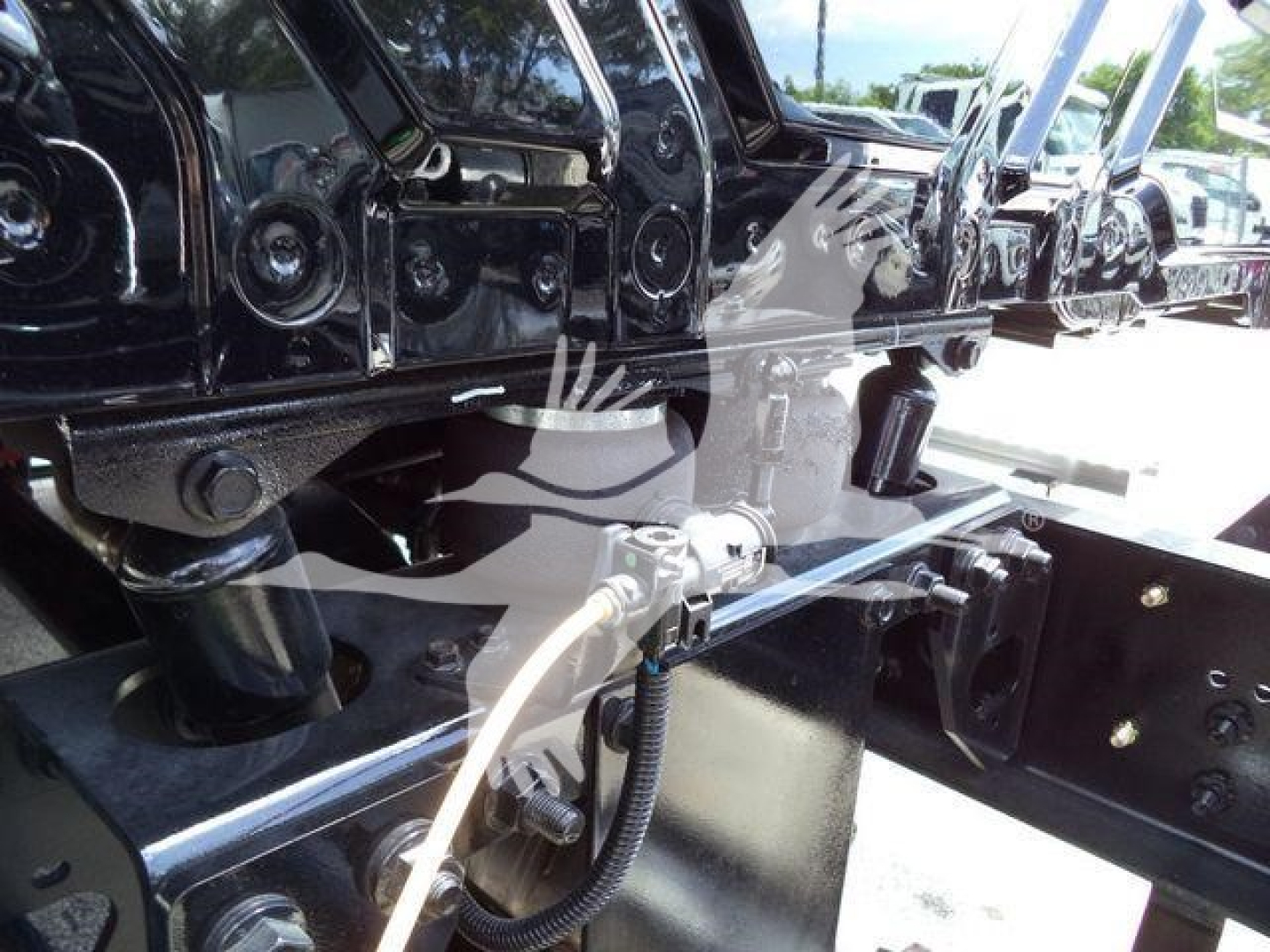 Truck chassis and undercarriage components showing frame and hitch area with hoses and wiring, MV model lineup in background.