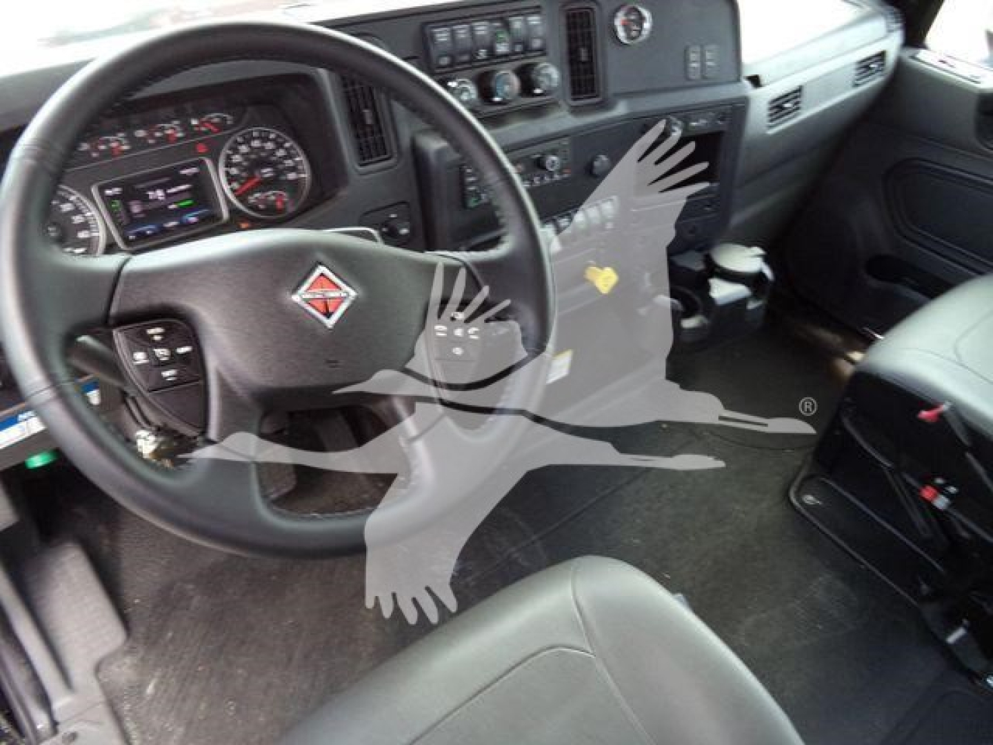 Interior of a 2026 International MV truck cab showing steering wheel with logo, dashboard, and front seats.