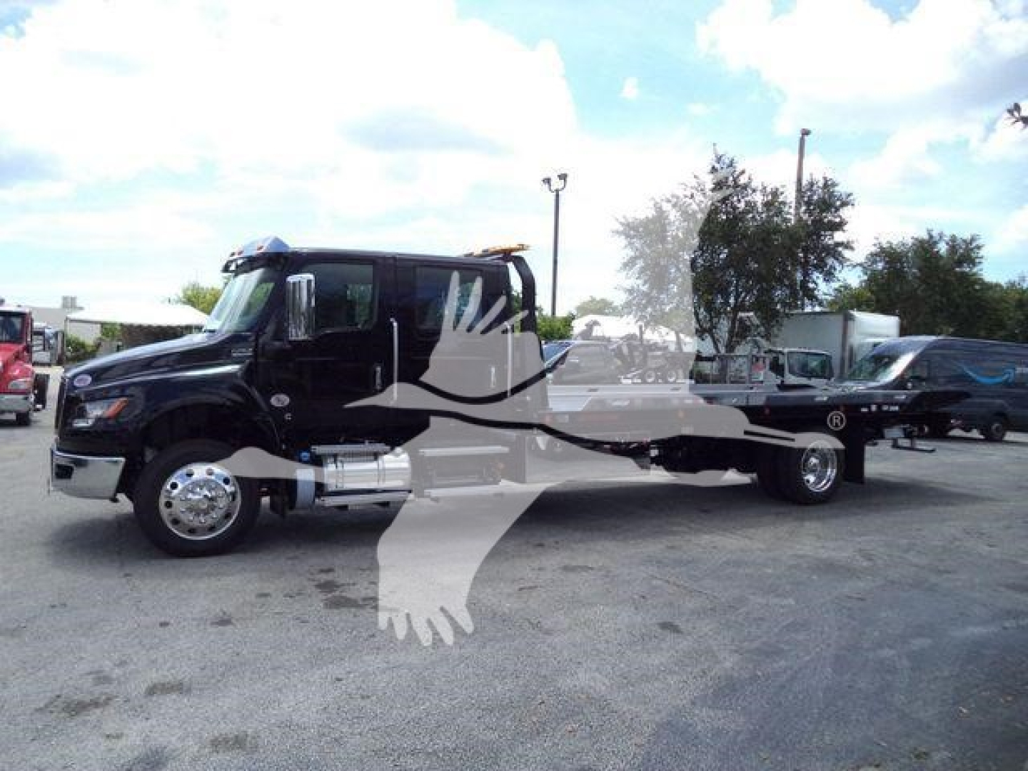 Black International MV rollback truck side view showing cab with chrome fuel tanks and flatbed gear. Visible text not legible.