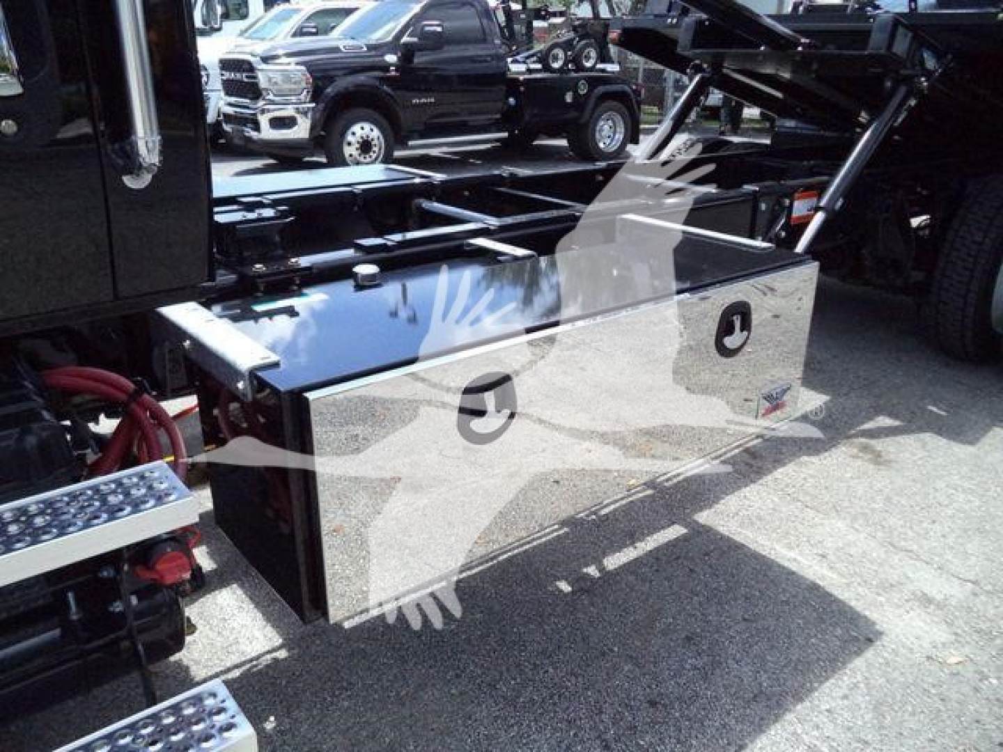 Trucks equipment storage box mounted on back of rollback truck, polished metal storage compartments with circular logo cutouts and red hoses nearby.