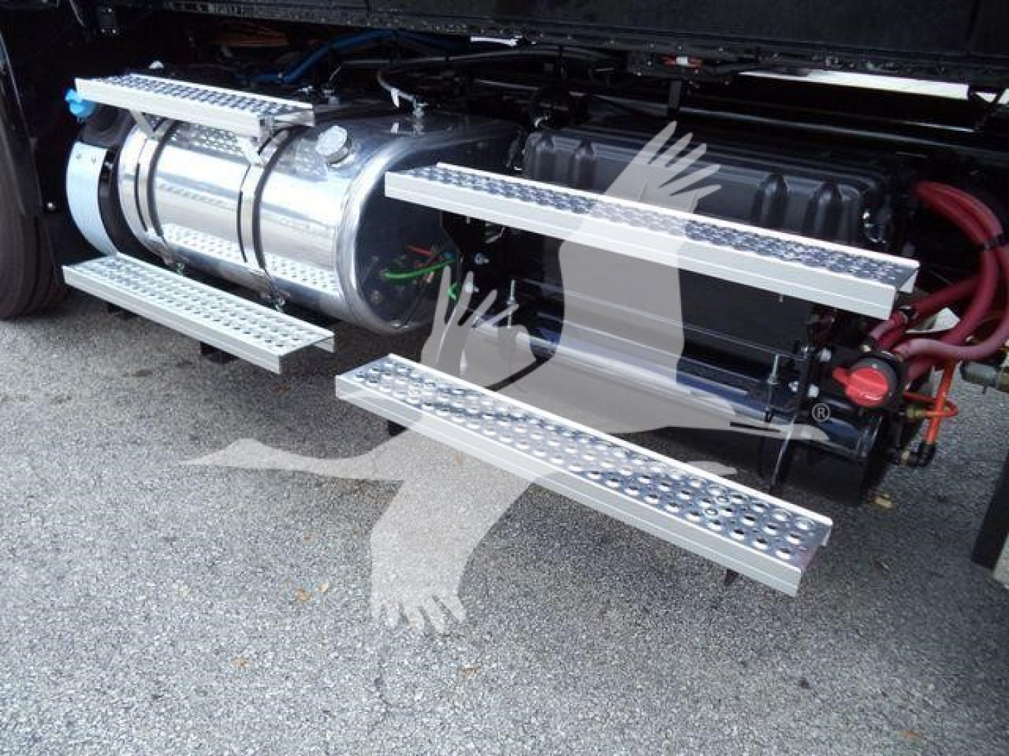 Truck side view showing chrome fuel tanks and side steps on a heavy-duty International MV rollback truck, with metal diamond-plate steps extended
