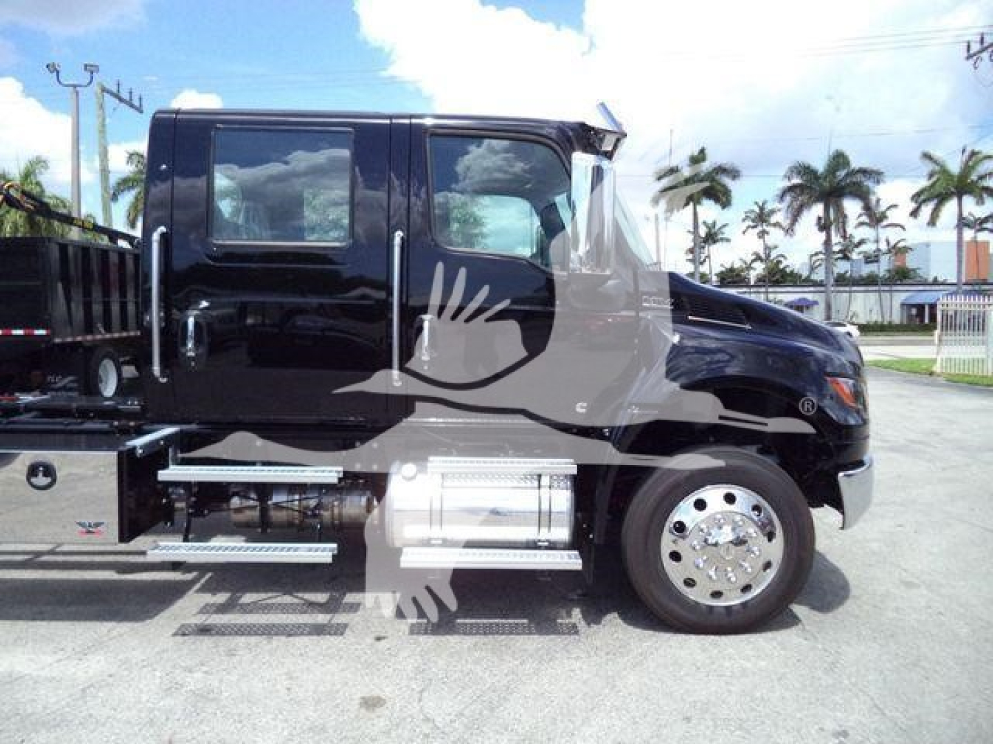 Truck side view showing International MV front cab with black paint, chrome wheel, and equipment rail; side steps and fuel tank visible.