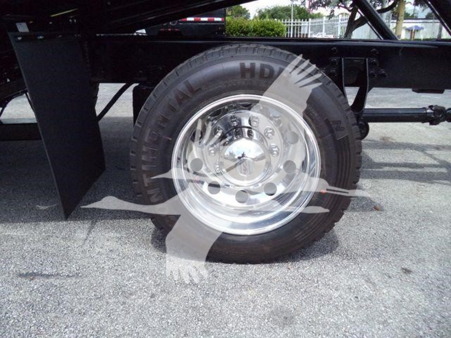 Truck wheel and axle close-up showing chrome hub, tire labeled Continental HDW, and undercarriage components.
