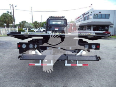 Truck bed of a 2026 International MV rollback truck showing rear lights and bumper with metal platform.