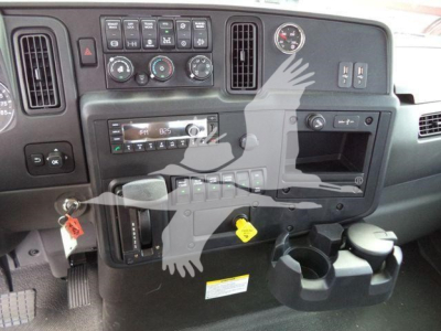Dashboard of a truck with controls, vents, and cup holders visible. Various gauges and knobs, including climate controls, radio, and warning stickers.