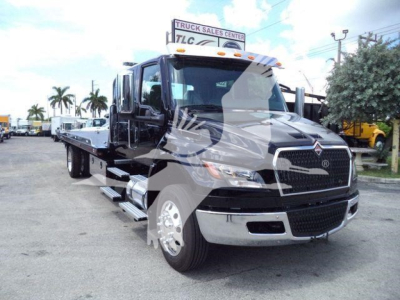 Truck bay showing 2026 International MV rollback tow truck with black body and chrome front grille, side mirrors, and flatbed.