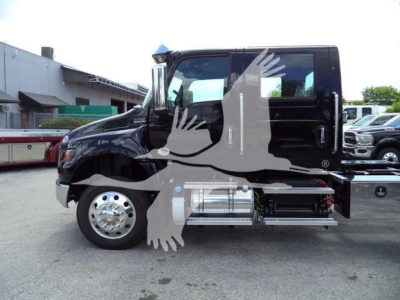 Truck cab side view showing black International MV with side steps and chrome fuel tanks. No visible text legible other than the watermark of a bird across the image.