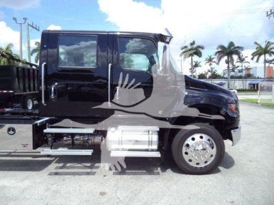 Truck side view showing International MV front cab with black paint, chrome wheel, and equipment rail; side steps and fuel tank visible.