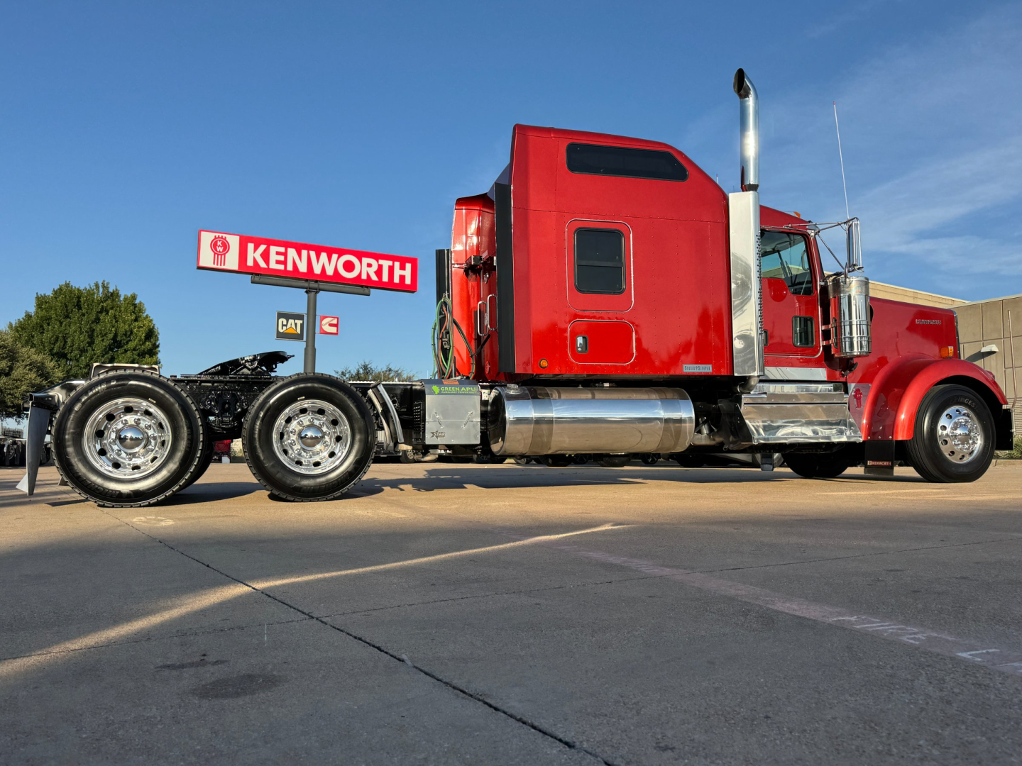 Kenworth W900L conventional sleeper truck in red, side view showing tractor with dual rear axles and chrome fuel tanks.