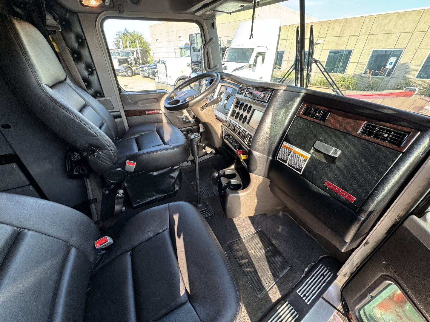 Kenworth W900L interior view of driver and passenger seats with dashboard and steering wheel.