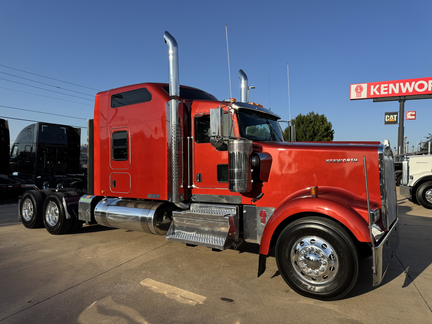 Kenworth W900L conventional sleeper tractor with red paint, chrome exhaust stacks, front chrome bumper, large front fender and twin rear axles.