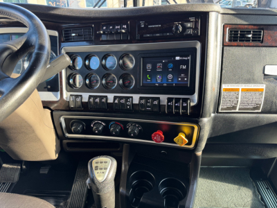 Kenworth W900L dashboard and center console showing instrument gauges, climate controls, and Kenworth touchscreen display.