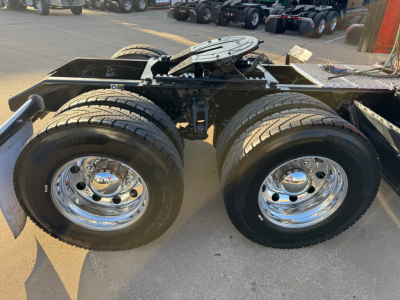 Kenworth W900L tractor chassis showing dual rear axles and chrome wheels with tires.