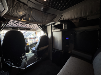 Kenworth W900L truck interior cab view from rear showing sleeper area, overhead compartments, and dash area with seats.