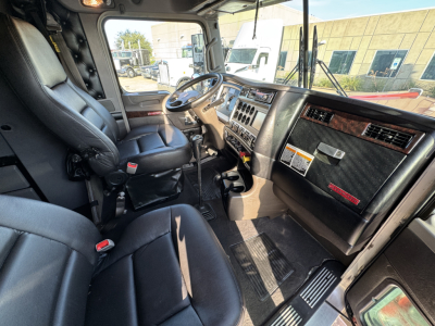 Kenworth W900L interior view of driver and passenger seats with dashboard and steering wheel.