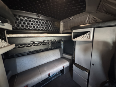 Interior of a Kenworth W900L cab showing sleeper berth area with quilted black leather panels and storage cabinets.