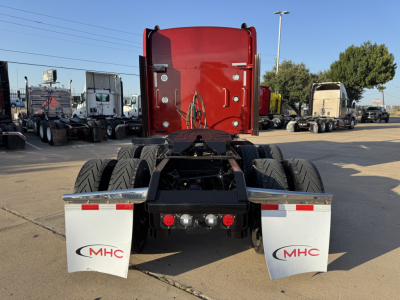 Kenworth W900L rear view showing dual rear axles and silver mudflaps with MHC logos.