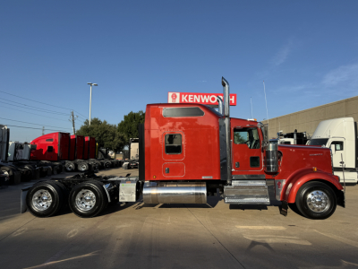 Kenworth W900L tractor with red cab, side view showing dual rear axles, chrome fuel tanks, and exhaust stacks.