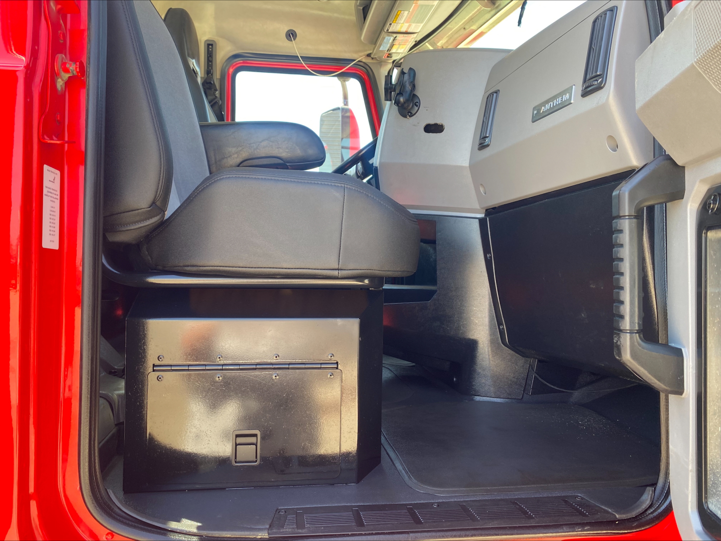 Cab interior of 2021 Mack Anthem tractor showing driver seat, dashboard, and open entry with floor and storage box visible.