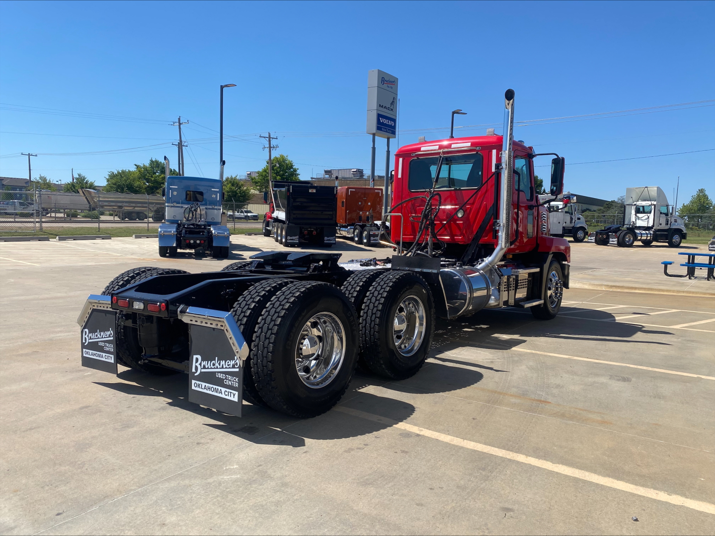 Truck chassis with red cab and black dual rear axles, showing Mack ANTHEM cab-over view and rear mud flaps