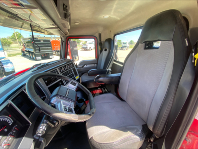 Truck cab interior showing steering wheel, dashboard, driver seat, and passenger seat in a Mack Anthem daycab.