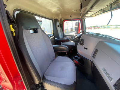 Interior cab of a 2021 Mack Anthem daycab showing driver seat and passenger seat, grey cloth upholstery, dashboard with steering wheel, and center console.