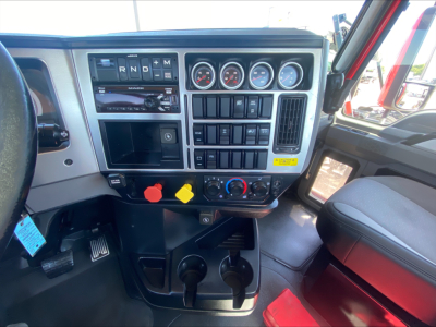 Dashboard of a Mack truck interior showing gauges, control switches, and gear selector area.