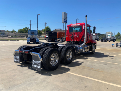 Truck chassis with red cab and black dual rear axles, showing Mack ANTHEM cab-over view and rear mud flaps