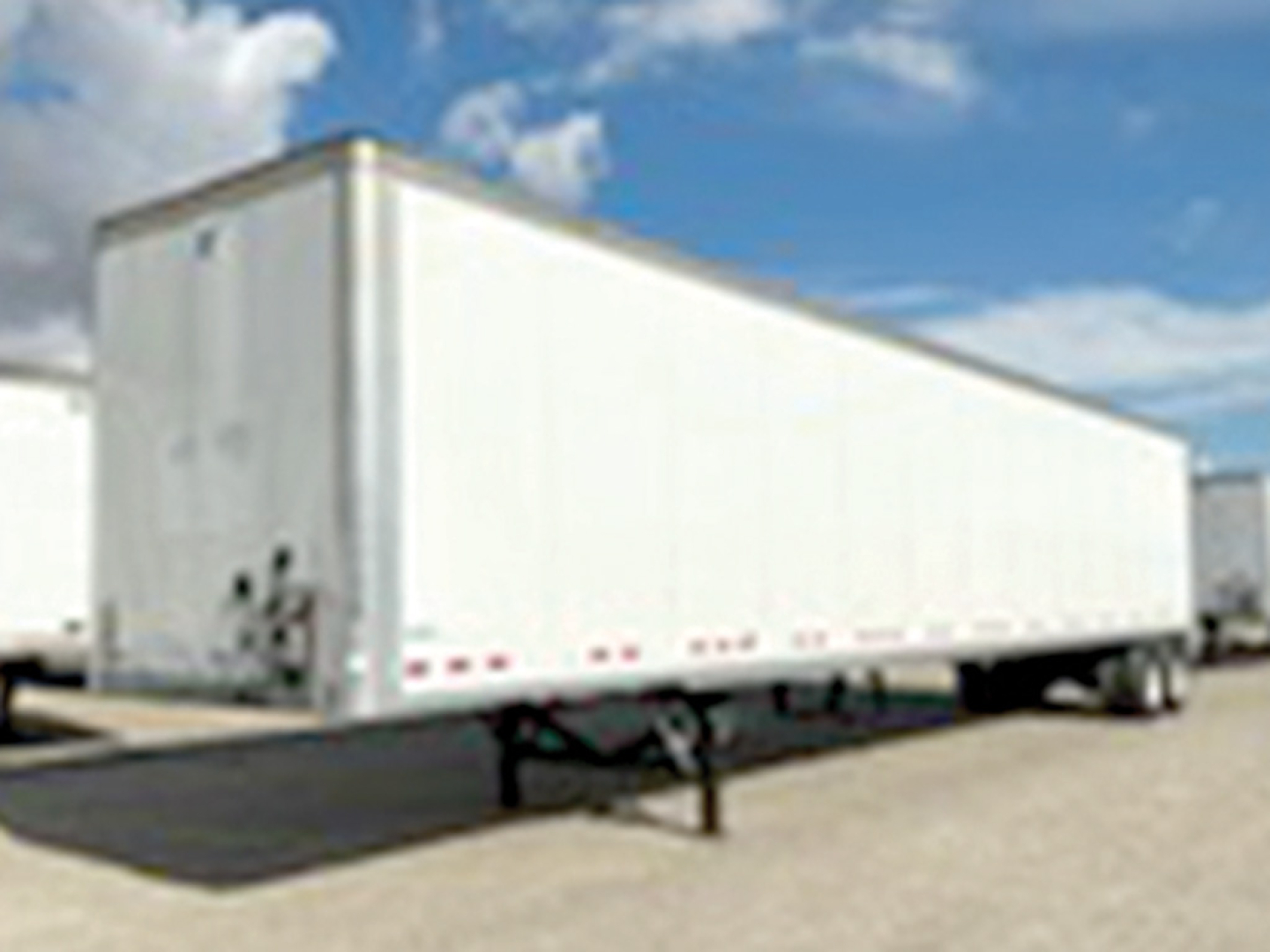 Trailer visible side view of a Vanguard VXP box trailer with white exterior, hitch, and support legs in a parking lot.