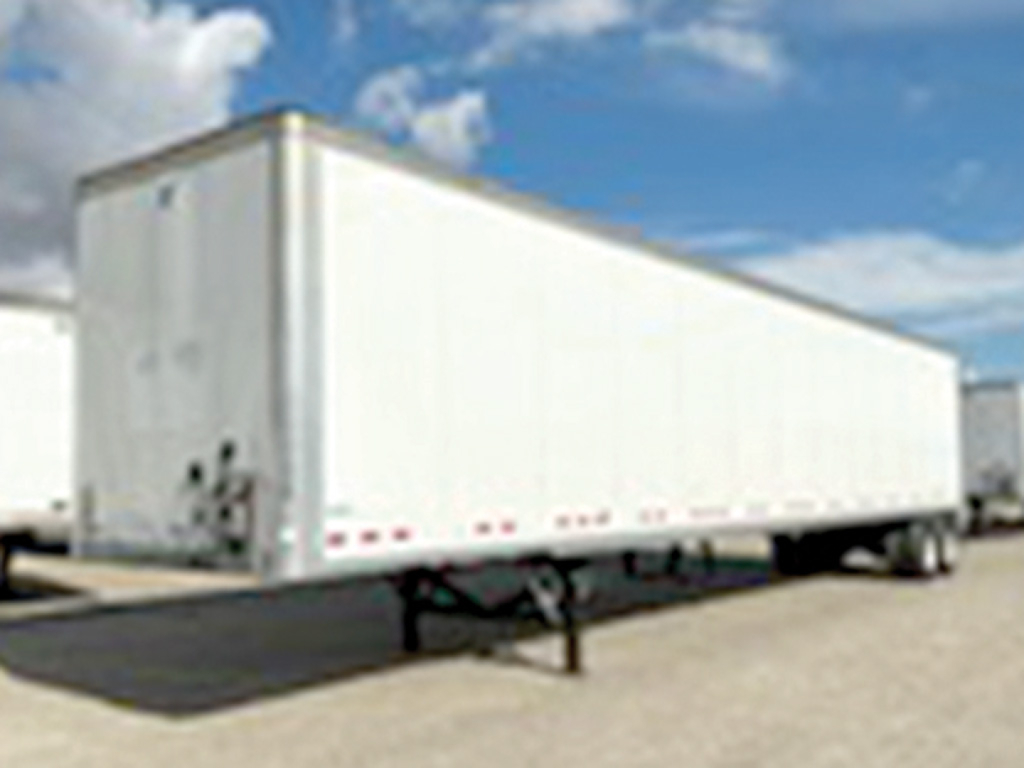 Trailer visible side view of a Vanguard VXP box trailer with white exterior, hitch, and support legs in a parking lot.