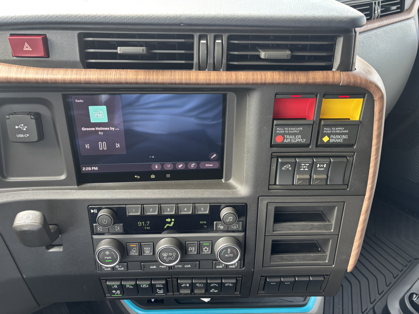 Dashboard view of a new 2027 Volvo VNL64T860 showing climate controls, infotainment screen, and control switches.