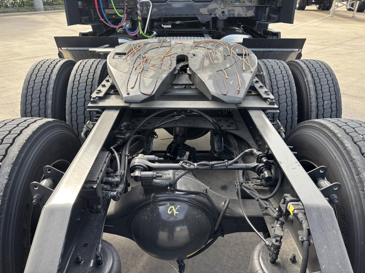 Rear view of a Volvo VNL truck chassis showing the fifth wheel plate, air lines, drive axles, and differential housing.