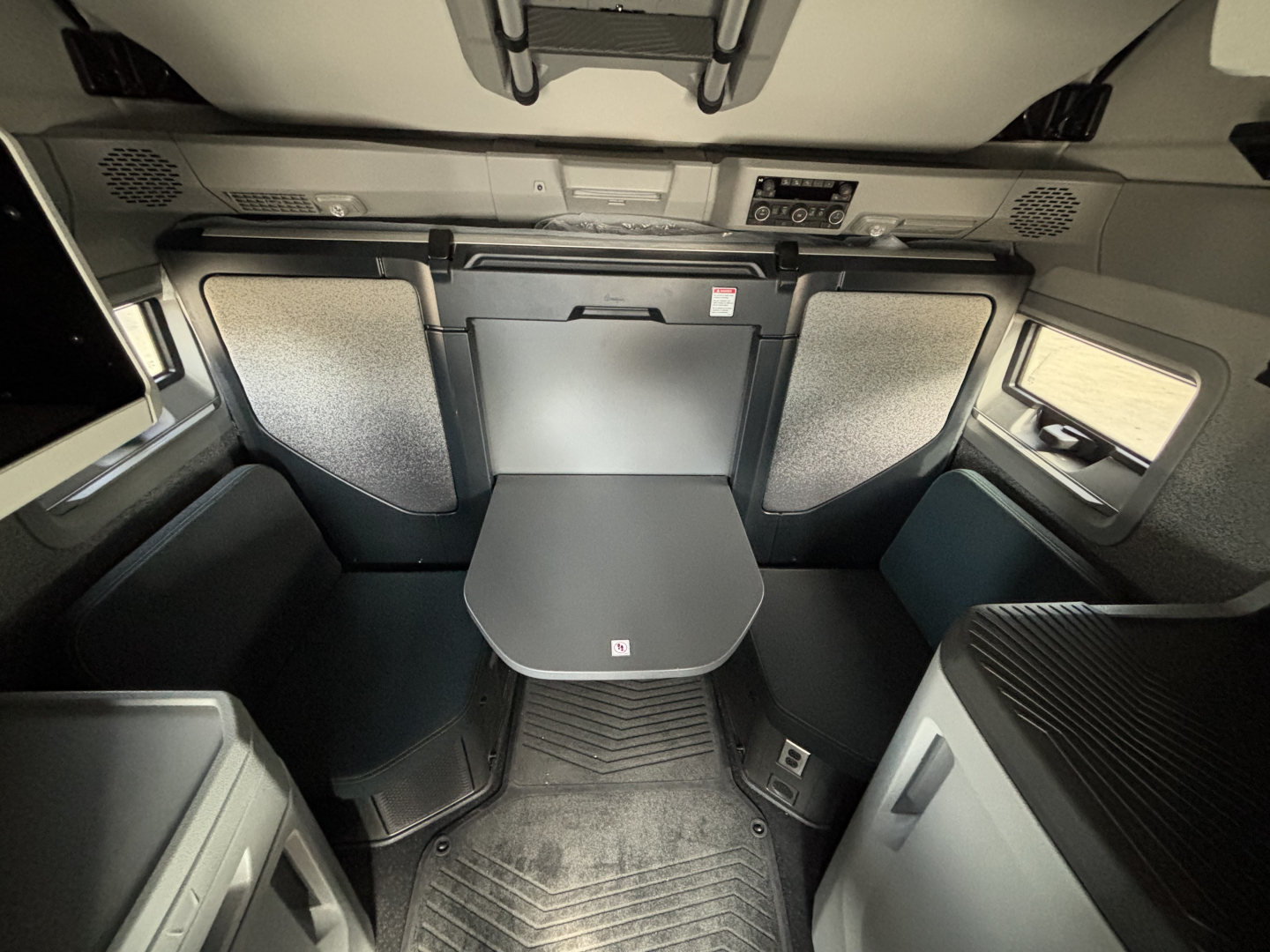 Volvo VNL64T860 sleeper cab interior showing side panels, overhead console, folding table, and seating area with textured panels.