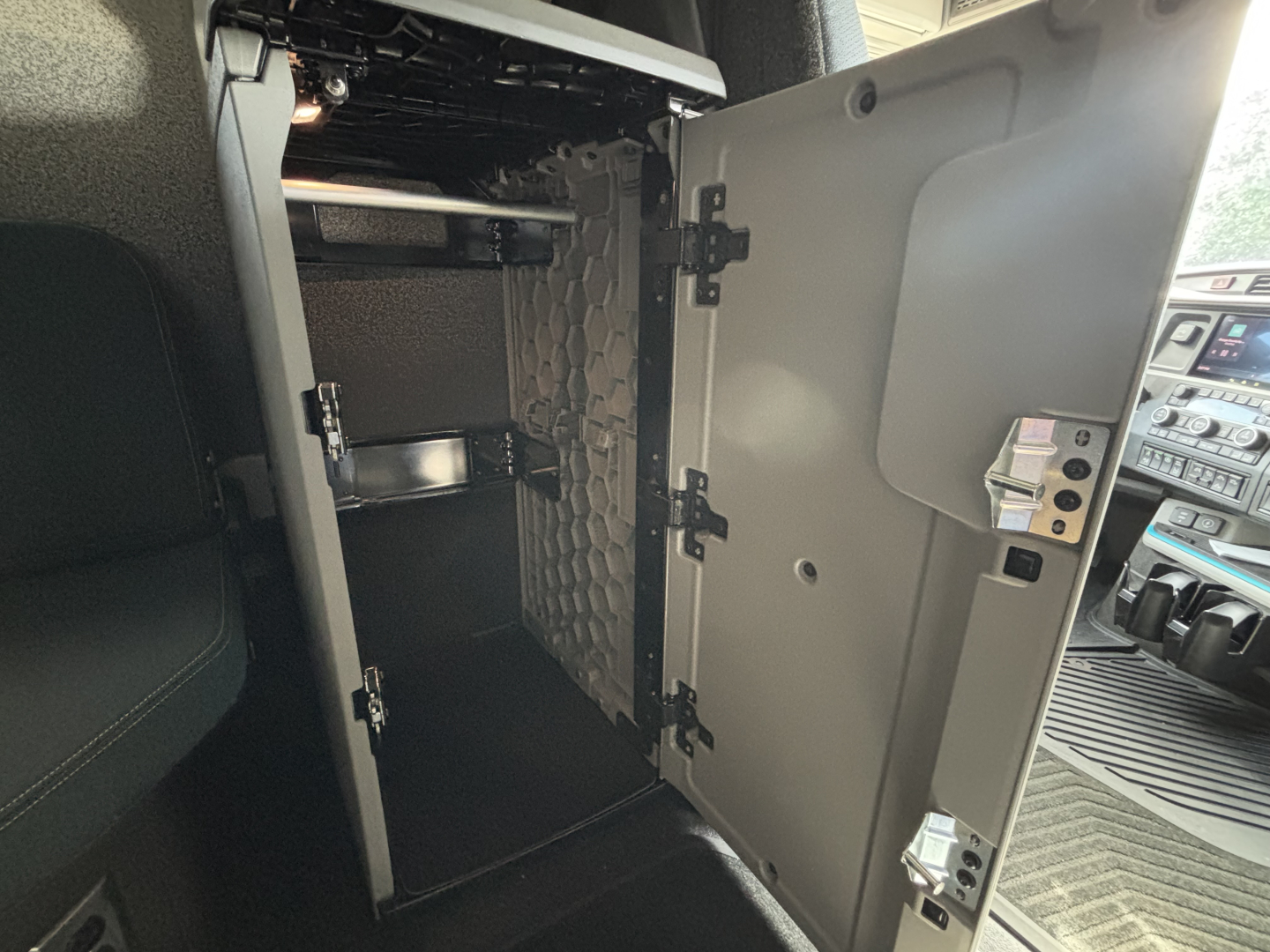Volvo VNL64T860 cab interior showing storage compartment with open door and metal shelves in the sleeper area.