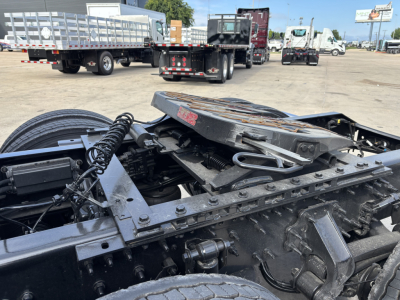 Front half of a Volvo truck chassis with exposed frame and suspension components, heavy-duty springs, drive shaft, and wheel hub visible.