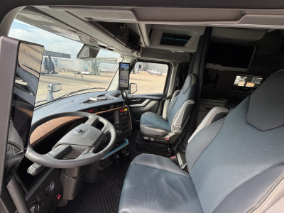 Volvo VNL cab interior showing steering wheel, driver seat, passenger seat, dashboard, and overhead storage in a new sleeper truck.
