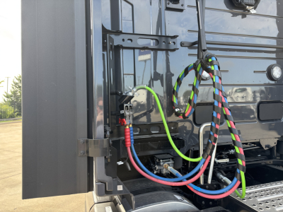 Volvo VNL64T860 exterior cab area showing colorful braided cables and hydraulic lines near front panel.